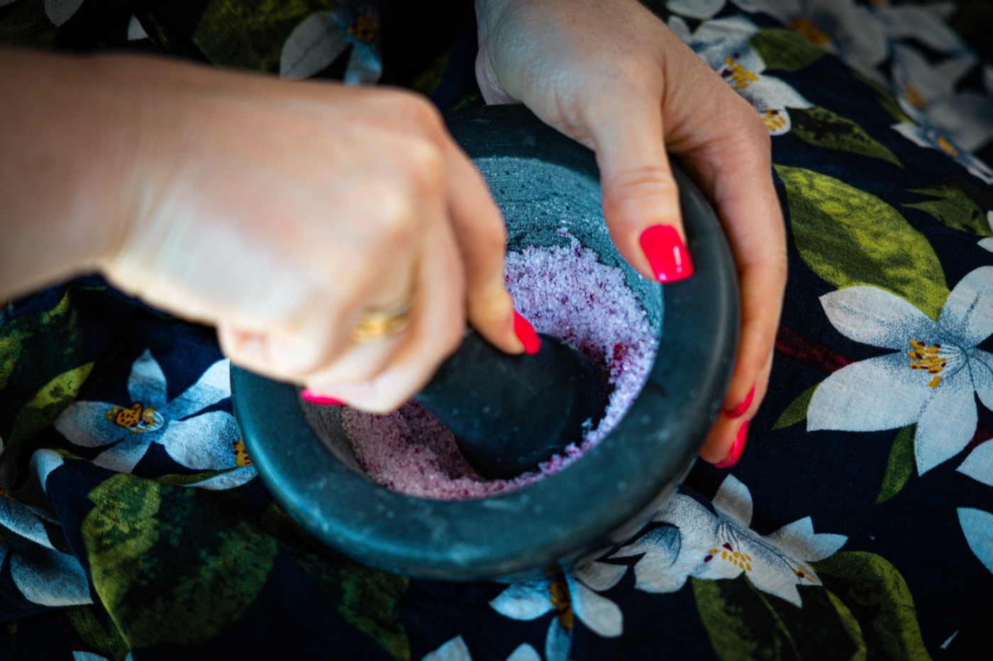 Hände zerreiben Blüten in einem Mörser – Herstellung von Naturkosmetik